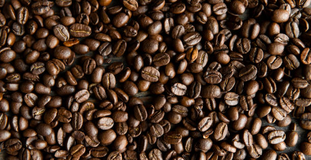 istock Roasted arabica coffee beans scattered on a wooden table. Fresh coffee beans. 1297618962