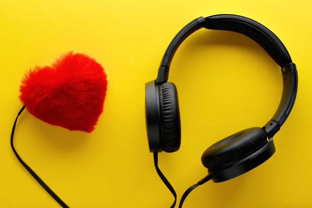 красное сердце и черные наушники на желтом фоне. любовь музыка образ жизни концепции. день святого валентина - romantic sky audio стоковые фото и изображения