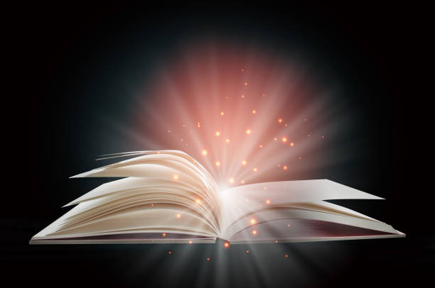 istock Open white paper fantasy book with shining pages isolated on black background 1297621695