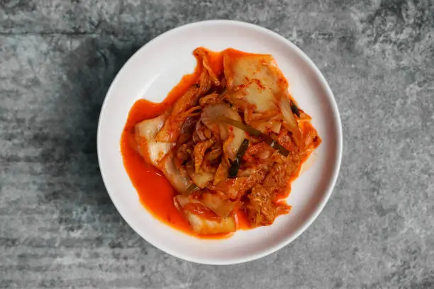 Top view Korean sliced cabbage kimchi on gray concrete table.