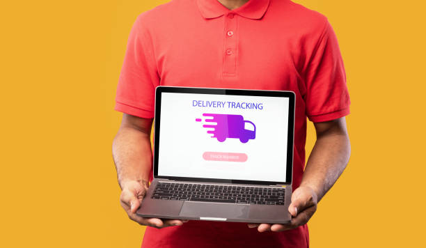 istock Young man holding laptop with delivery tracking app 1297622096