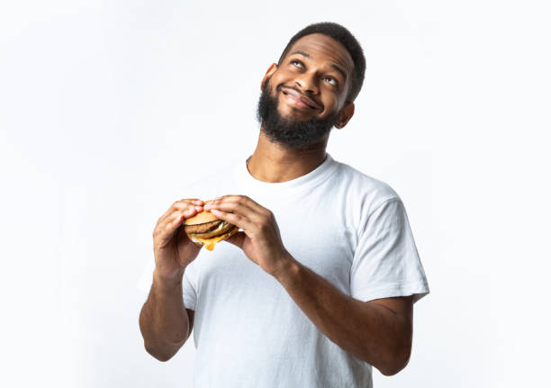 istock Happy Black Millennial Guy Holding Tasty Burger, White Background 1297622729