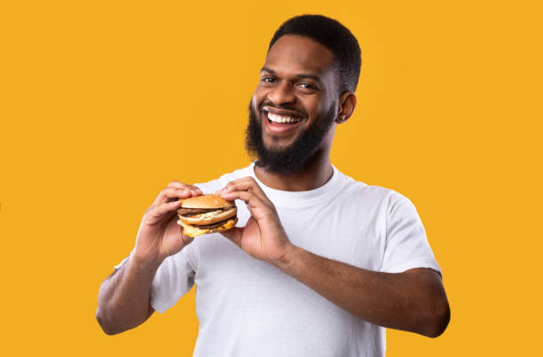 istock Happy African American Guy Posing With Burger On Yellow Background 1297622864