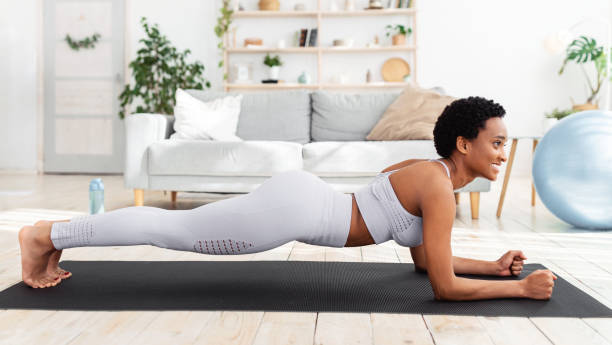 séance d’entraînement à domicile. formation noire de femme sur le tapis de yoga, faisant la pose de planche de coude, renforçant ses muscles d’abdos - core workout photos et images de collection