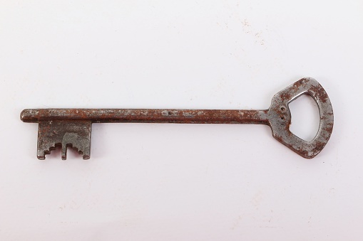 old rusty key is lying on a white background