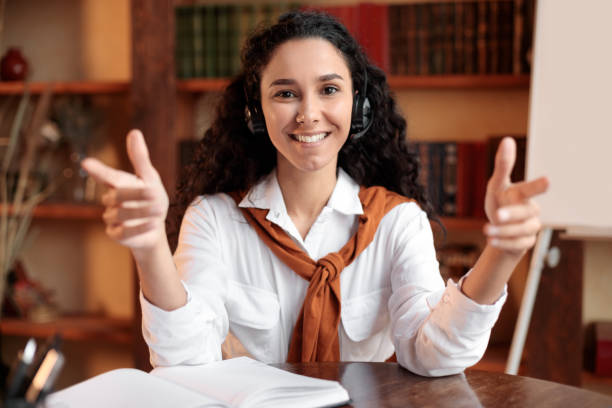istock Woman sitting at desk, talking to camera wearing headset 1297624094