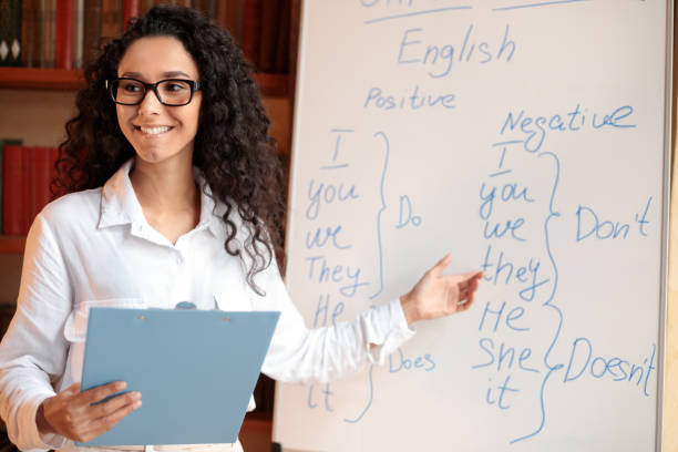 istock Smiling female teacher pointing at whiteboard, explaining rules 1297624426