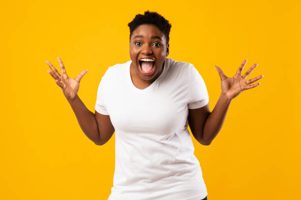 istock Plus-Size African Woman Screaming In Excitement Posing On Yellow Background 1297624595
