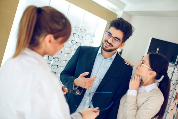 istock Smiling couple selecting eyeglasses in optical store 1297627053