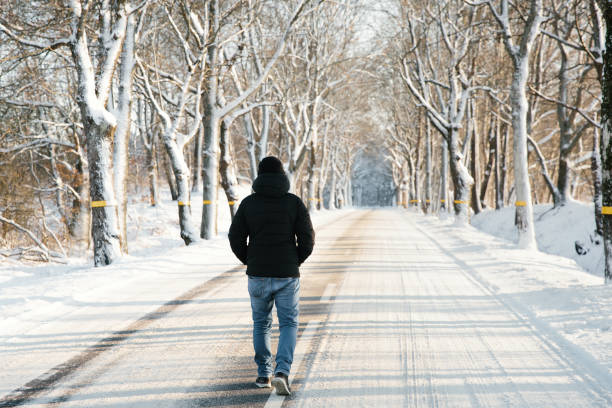 istock Man walks alone on snowy road. Travel alone concept. Faceless. 1297627270