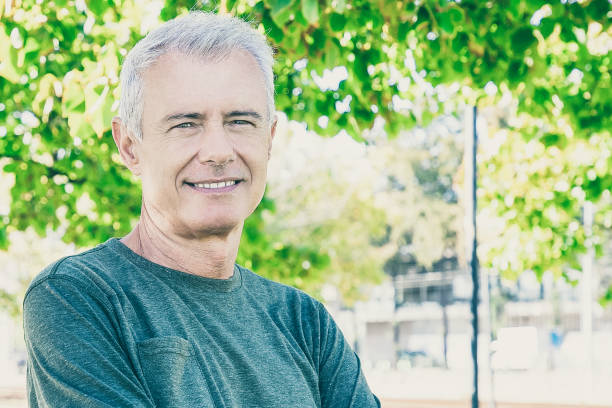 istock Happy mature man with crossed arms standing outside 1297627471