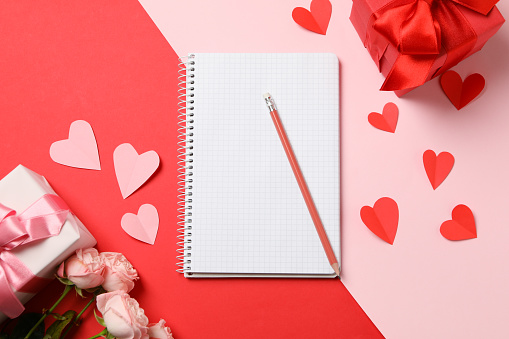 Concept of Valentine's day with empty copybook on two tone background