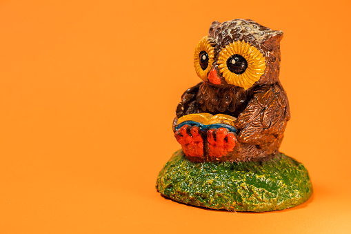 Small handmade ceramic owl with orange background.