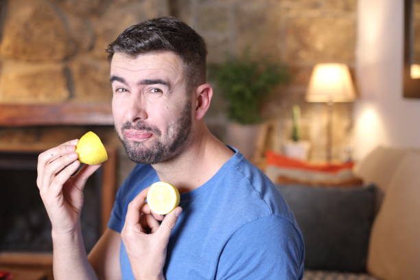 Man tasting a raw lemon Man tasting a raw lemon. sour face stock pictures, royalty-free photos & images