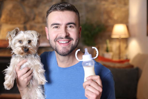 istock Man holding small dog and feeding bottle 1297629003