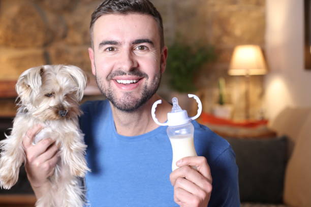 istock Man holding small dog and feeding bottle 1297629110