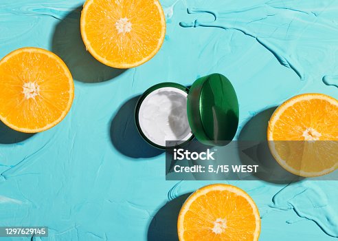 istock Cosmetic moisturizing face cream with vitamin C. Oranges and jars with cream on a blue background top view 1297629145