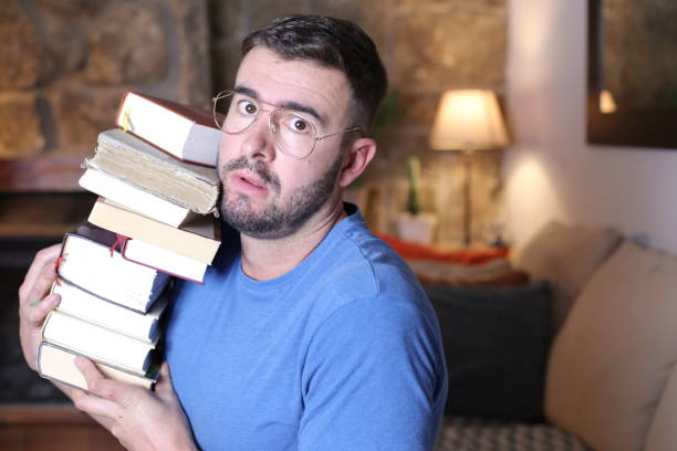 istock Man holding heavy pile of books 1297630585