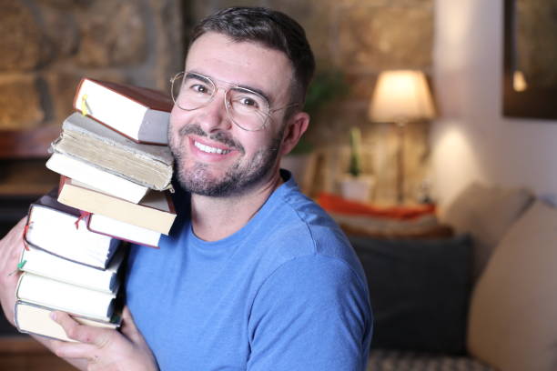 istock Man holding heavy pile of books 1297630652
