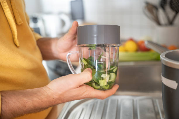 istock Man makes a green healthy smoothie in the kitchen 1297630675
