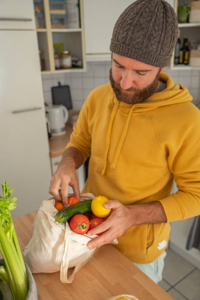 istock Man puts away vegetable groceries in the kitchen 1297631259