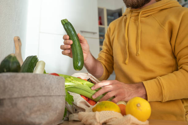 Man puts away vegetable groceries in the kitchen