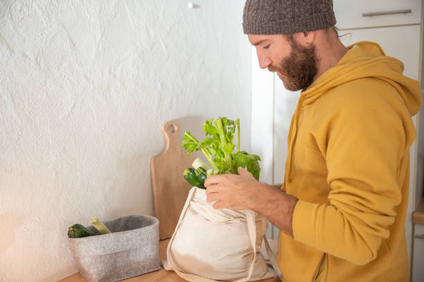 istock Man puts away vegetable groceries in the kitchen 1297631352