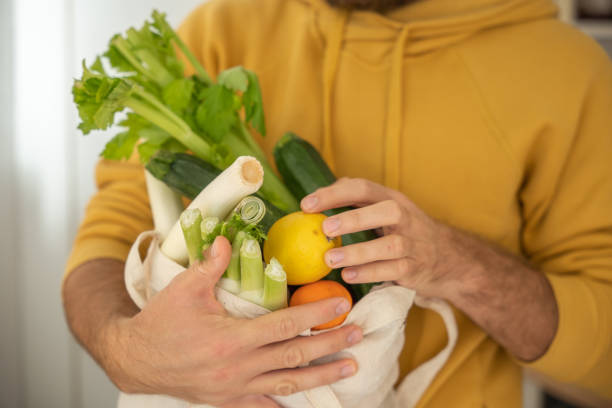 istock Man puts away vegetable groceries in the kitchen 1297631523