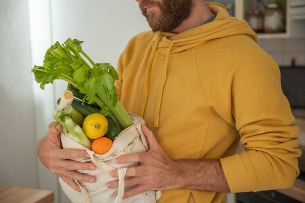 istock Man puts away vegetable groceries in the kitchen 1297631679