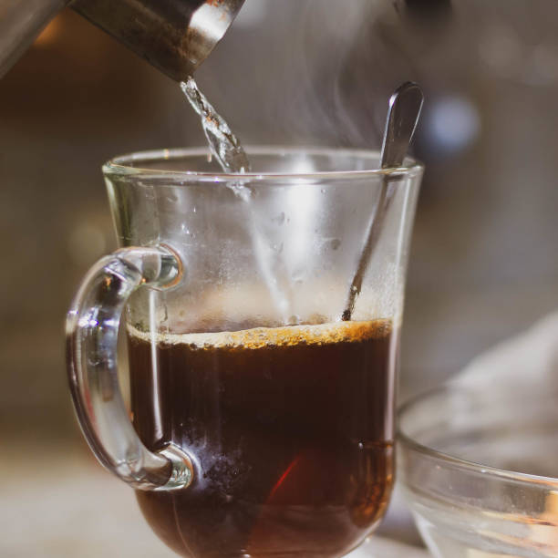 istock Pour hot water into a glass mug with instant coffee from the kettle 1297632761