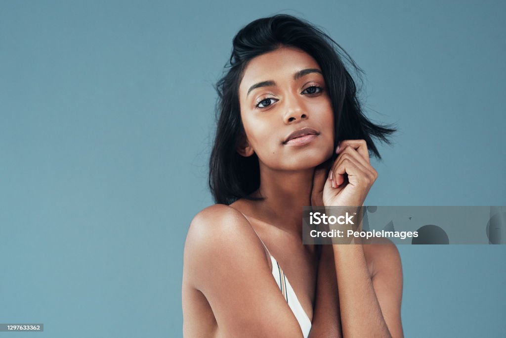 Her beauty makes it hard not to stare Shot of a beautiful young woman posing against a blue background Women Stock Photo
