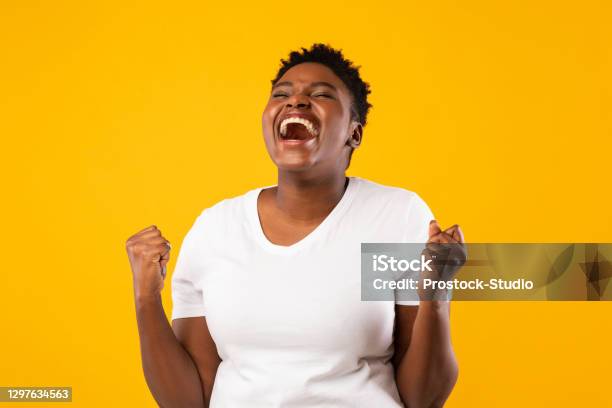 Joyful Black Woman Shouting Shaking Fists Posing Over Yellow Background Stock Photo - Download Image Now