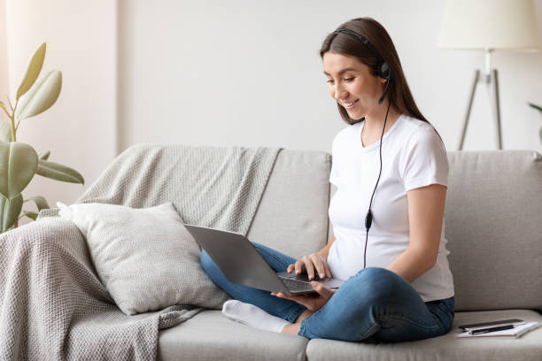 pregnant woman in headset using laptop at home, studying or working online - baby animals audio imagens e fotografias de stock
