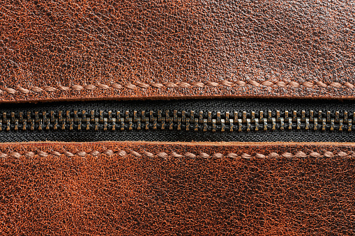 Metal zip closed lock. Zipper on brown leather surface macro close up view
