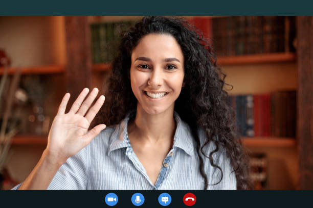 istock Woman waving to camera having online conference call 1297635991