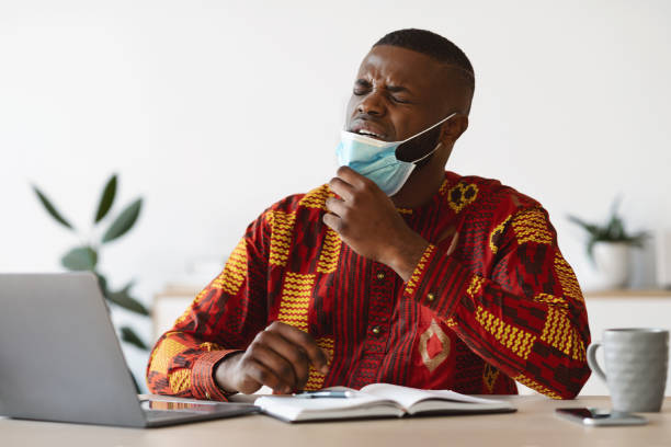 istock Young African Man Taking Off Medical Mask At Work, Can Not Breathe 1297636018