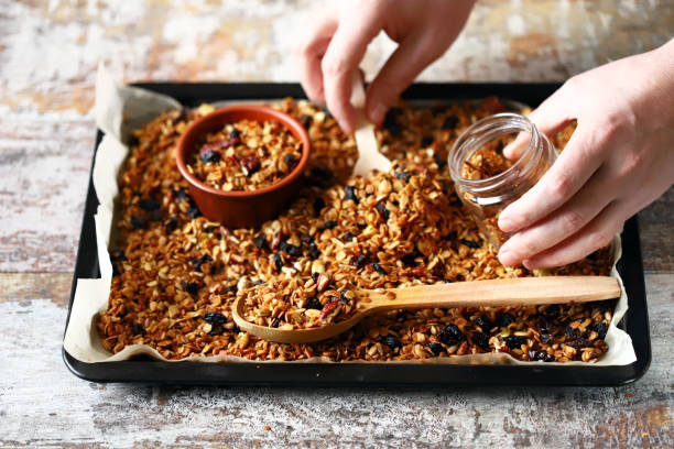 Homemade granola on a baking sheet. Freshly made homemade granola on a baking sheet. Granola in a wooden spoon and in a jar. Selective focus. Healthy diet concept. Keto diet. granola photos stock pictures, royalty-free photos & images