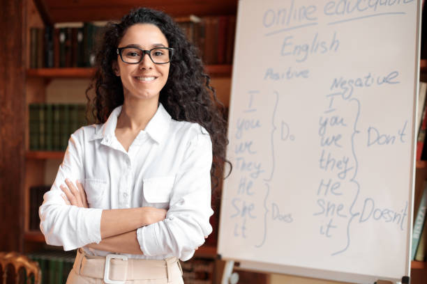 istock English teacher standing at whiteboard, posing at camera 1297637158