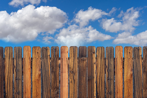 Aged wooden fence with cloudy blue sky