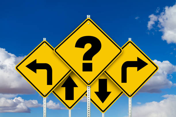 Caution yellow road signs with question mark and arrows with a blue sky and clouds