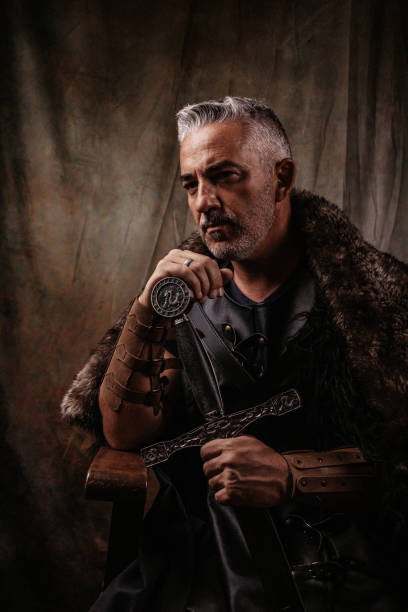 istock Thoughtful looking fantasy knight sitting on a simple wooden throne 1297638499