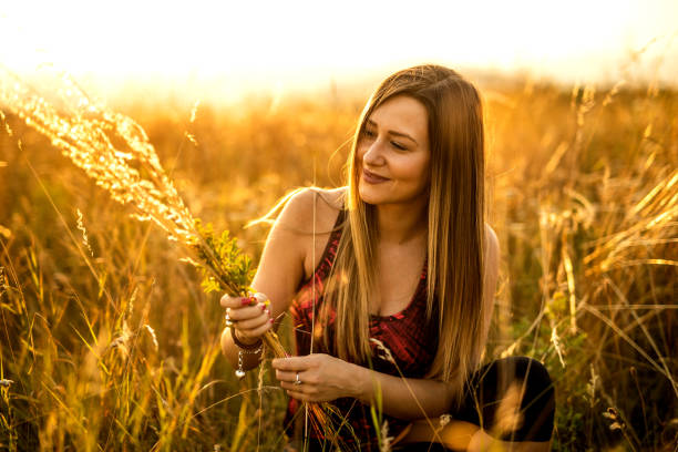 istock Smiling woman crouching in golden wheat field 1297638663