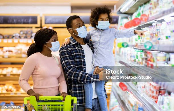 Family Shopping During Coronavirus Pandemic Black Family With Child Wearing Face Masks Purchasing Food At Supermarket Stock Photo - Download Image Now