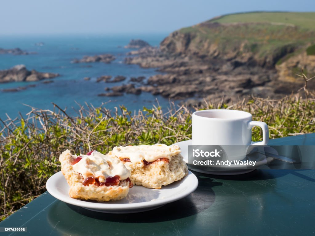 Cream tea Cornish cream tea, including scones with jam and clotted cream, with a seascape background at Lizard Point, Cornwall, England. Cornwall - England Stock Photo