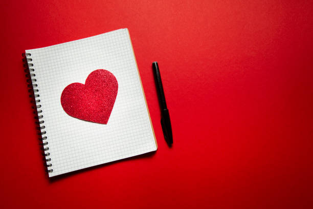 istock checkered notebook with valentine heart and pen on red background 1297641941