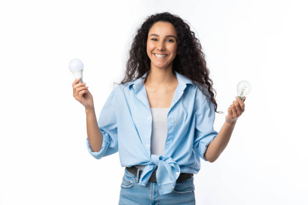 istock Cheerful Lady Holding Two Lightbulbs Standing Over White Studio Background 1297642834