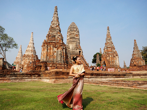woman in Thai traditional costume with ancient pagoda at temple at Ayutthaya, Thailand (Wat Chai Wattanaram)