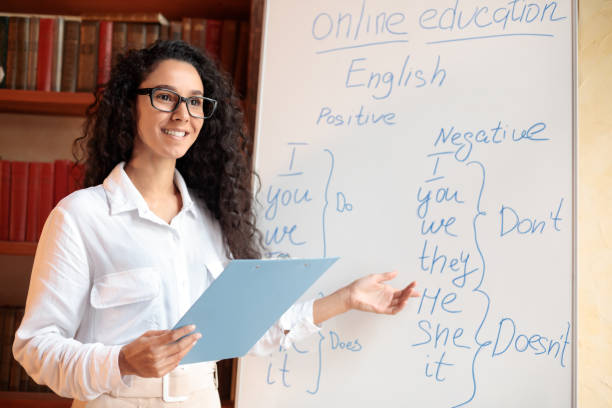 istock Smiling female teacher pointing at whiteboard, explaining grammar rules 1297643333