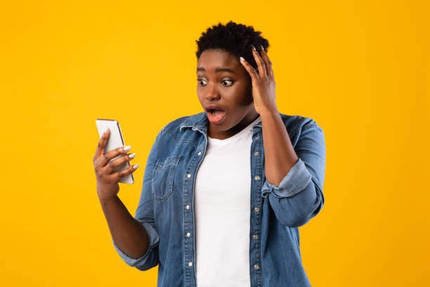 istock Shocked Black Woman Using Phone Reading Bad Message, Yellow Background 1297644255