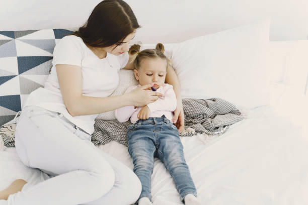 istock Mother with thermometer is sitting near daughter 1297644367